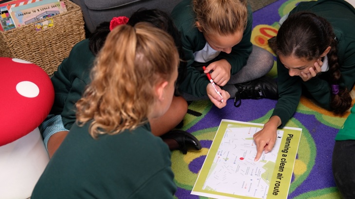 Group of school girls working together to plan a clean air route
