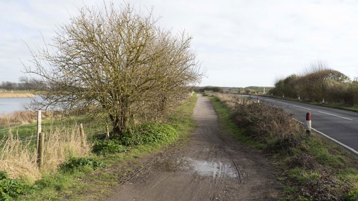 before photo of national cycle network route 2 path near Camber Road in East Sussex. Unmade muddy path, narrows, undulating. 