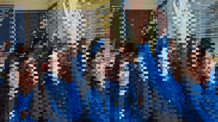 pupils in classroom raising their hands