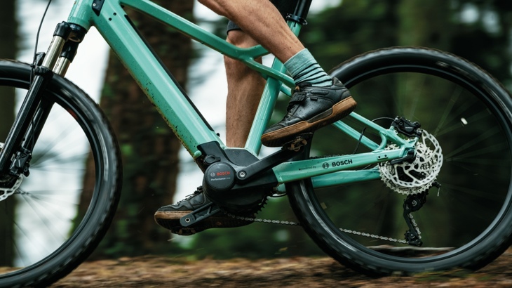 A close up image of a Bosch e-bike rider navigating a woodland path