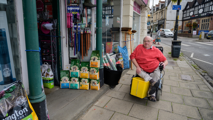A man using a wheelchair outside of a homeware store on a busy street in Bristol 