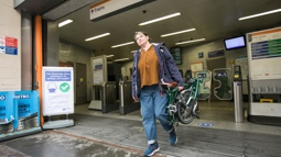 A woman carries her folding cycle out of a train station in London