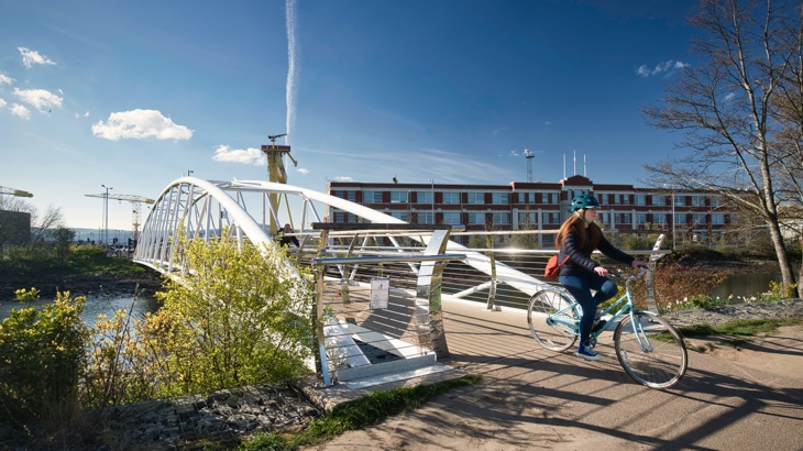 A female commuter crossing a traffic-free bridge in Belfast on a sunny day with a clear sky during winter