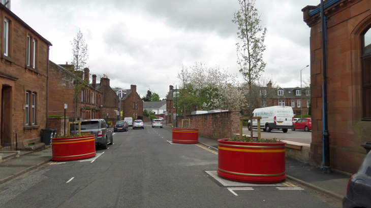 Large red planters filled with vibrant flowers located along a street to slow traffic down
