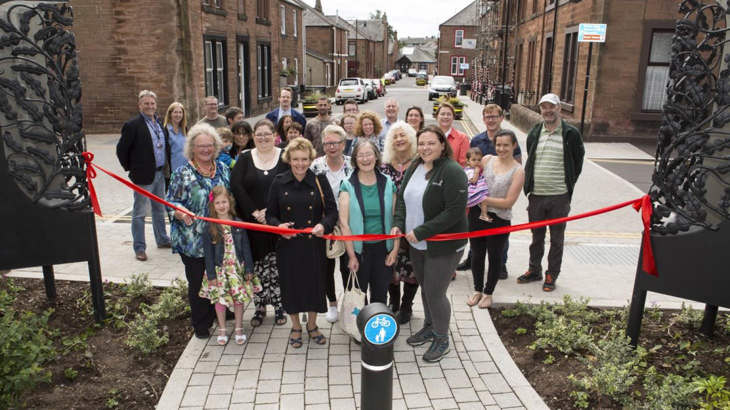 Walk Wheel Cycle Trust staff and local community members gather together to cut a ribbon and unveil the changes made to improve their high street