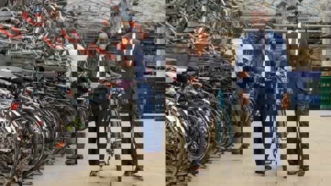 man and woman pushing bike at train station bike storage facility