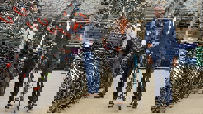 man and woman pushing bike at train station bike storage facility