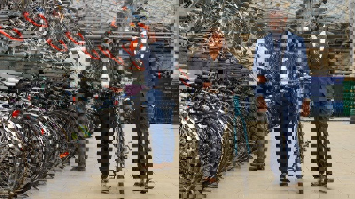 man and woman pushing bike at train station bike storage facility