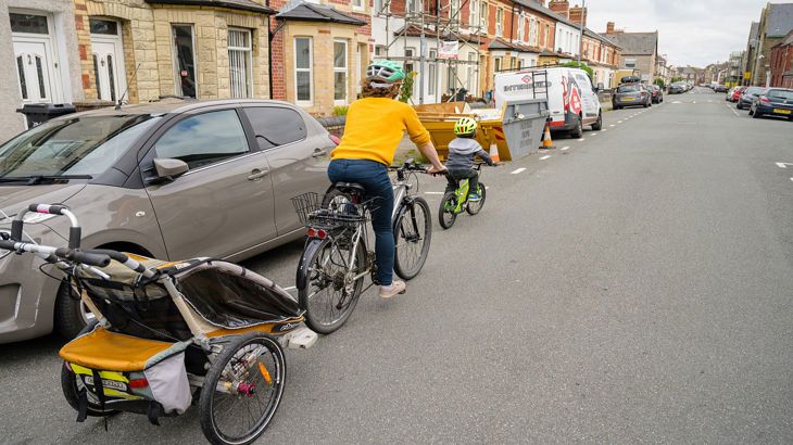 Family cycling with a bike trailer along a residetial road