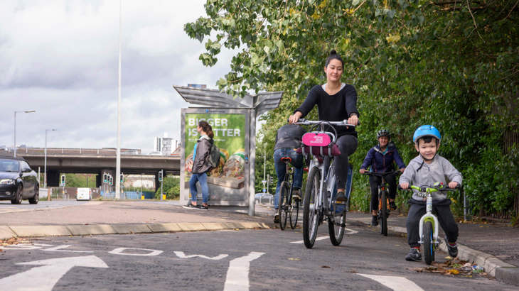 Mum and child cycling along a dedicated cycle lane past a bus stop.