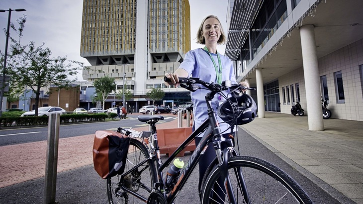 Pharmacist standing outside her workplace with her bike