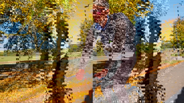 A young man cycles along a cycle route on a sunny autumnal day 