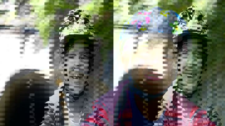 Close up of a child smiling wearing a helmet on a traffic-free National Cycle Network route