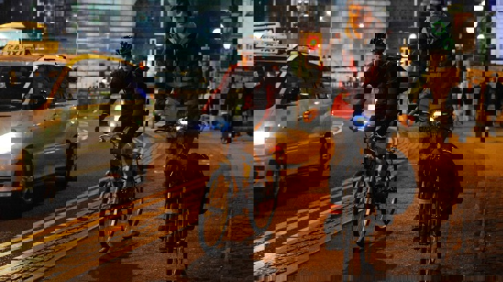 Two men cycling in the dark in a busy city landscape