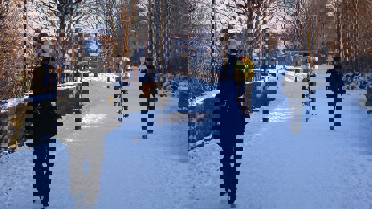 A cyclists rides through the snow on a shared path with walkers
