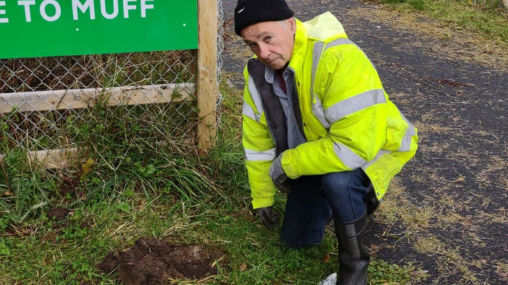 Walk Wheel Cycle Trust volunteer, Cathal Monaghan, planting bulbs in front of the village welcome sign on the National Cycle Network.