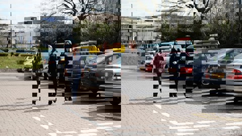 Three women walk through a car park in an industrial setting
