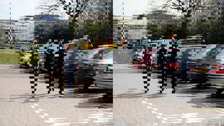 Three women walk through a car park in an industrial setting