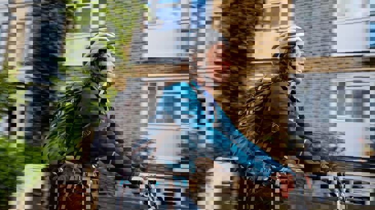 Woman cycling on residential street wearing helmet and backpack