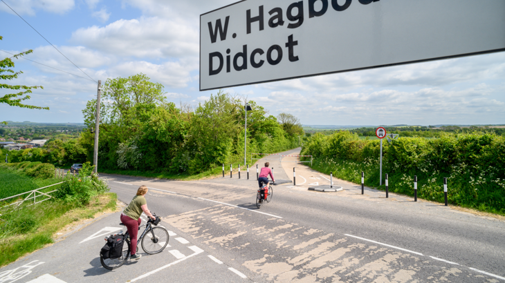 two people cycle towards a newly repurposed route, showing new entrance to the route following improvements.