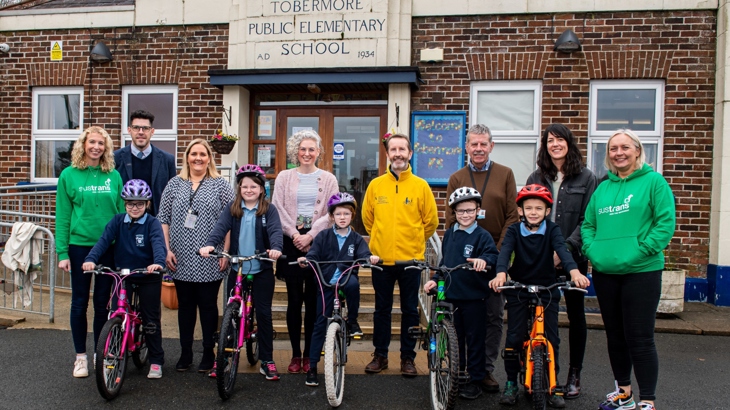 Children with bikes and adults stand in front of Tobermore Primary School.