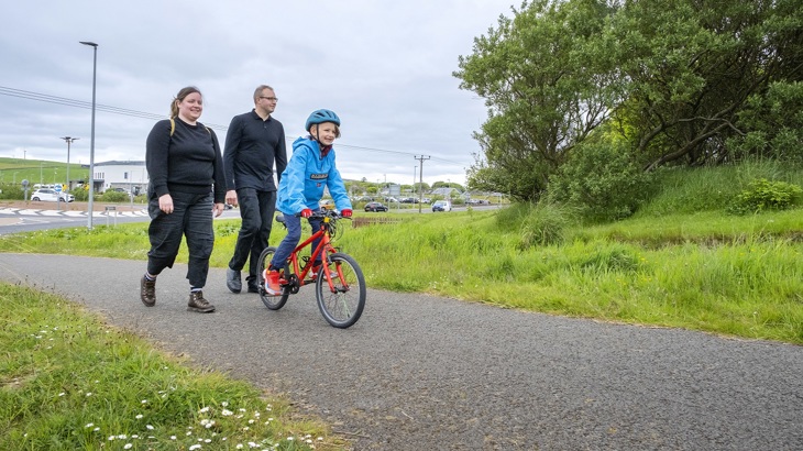 Adele and Rikki Lidderdale are pictured walking in Papdale Park, Orkney. They are following their son Remi, who is riding a bicycle.