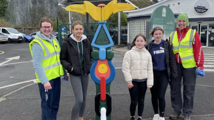 Young people from Ballycastle and Rathlin Island stand beside a Millennium Milepost they repainted with volunteer coordinator Rachael Ludlow-Williams