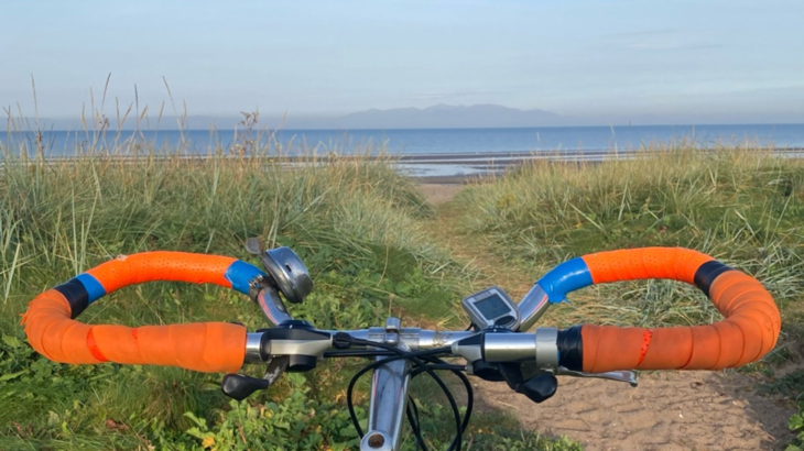 Bicycle handlebars in front of a beach on a clear day