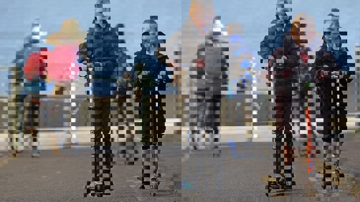 Two schoolboys in black coats on scooters ©2018, Neil Hanna