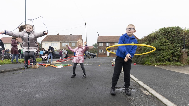 three children hula hooping on the street