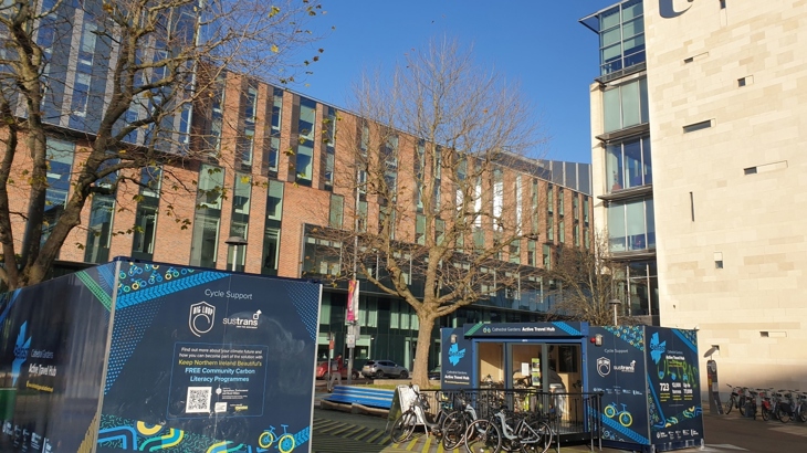 An active travel hub sits between high rise buildings in a city centre with a clear blue sky above.