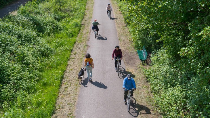 An aerial view of a range of people walking and cycling on National Cycle Network Route 6 in Alexandra Park, Manchester.