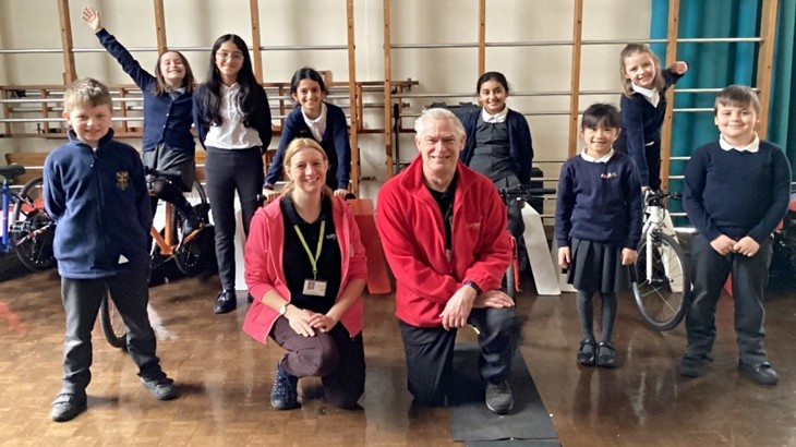 School children and Walk Wheel Cycle Trust schools officers Gemma and Eric smile at the camera in the school gymnasium after a Bike It activity.