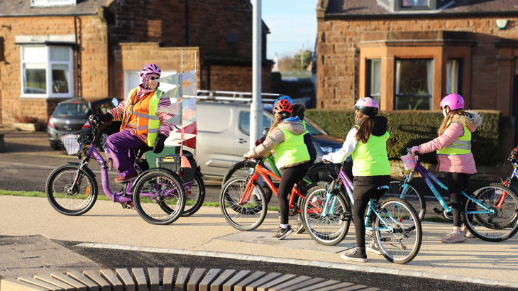 A woman leading a group of schoolchildren on bikes