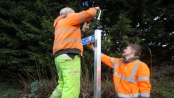 two men install a sign on a walking and cycling route
