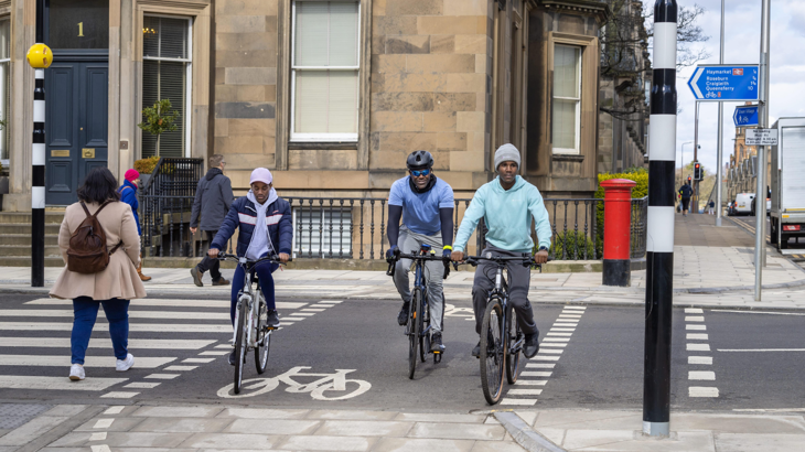 A group of people walking and cycling across a road.