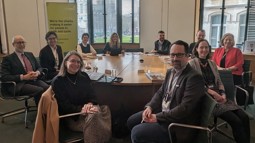 A group of men and women, members of Parliament and representatives of Walk Wheel Cycle Trust and other organisations, sit in work attire around a table.