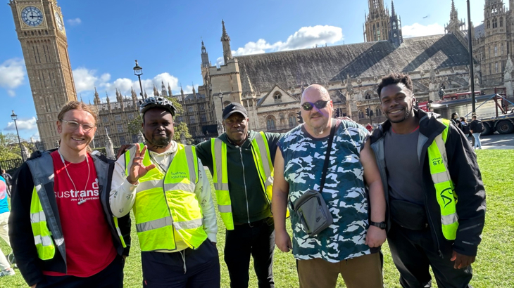 Walk Wheel Cycle Trust staff with Riverside Hostel customers standing in a line in front of Big Ben, smiling.