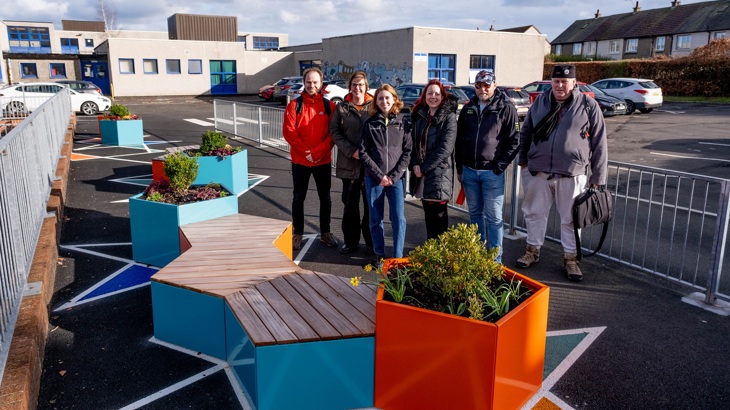 Six people representing the Easter Carmuirs Pocket Places project partners are shown standing by the newly-installed seating area.