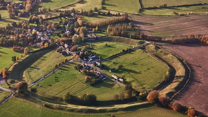 The village of Avebury and stone circles viewed from above, showing the shadows of the trees and stones and the National Cycle Network passing through