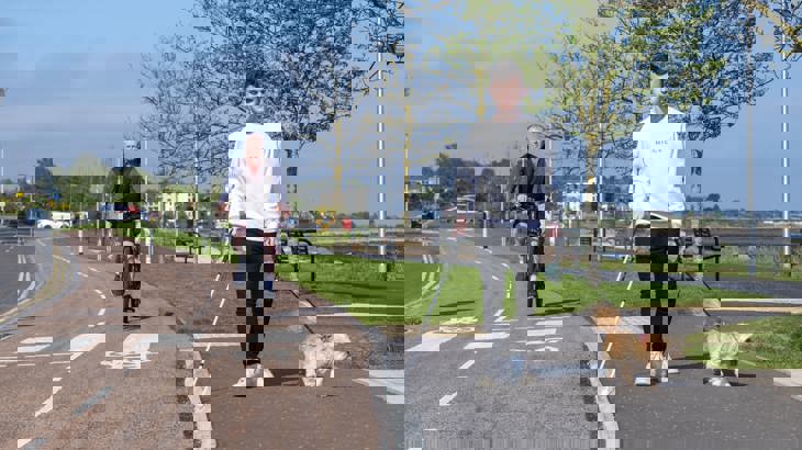 Elderly Male Cyclist And Visually Impaired Man Walking Dog