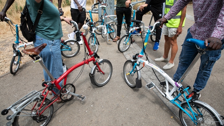 A group of people receive cycle training alongside their bicycles. Their faces cannot be seen.