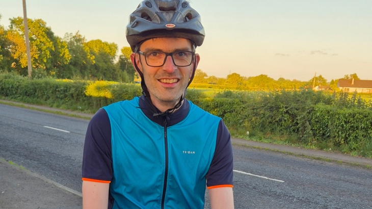 A man wearing a helmet and glasses is pictured on a clear summer evening outdoors.