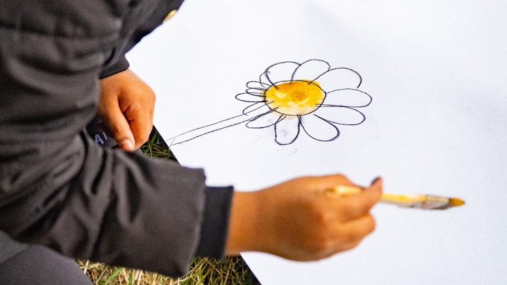 Engagement session in Niddrie-Bingham as part of the mural project. Consultation with local schools and families highlighted a desire for the design to recognise nature in the area. Photo shows a child drawing a flower.