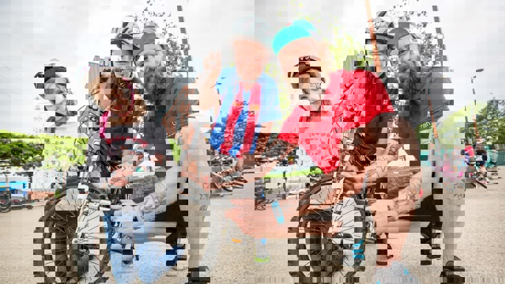 bike mechanic using pump to inflate Tyre with children