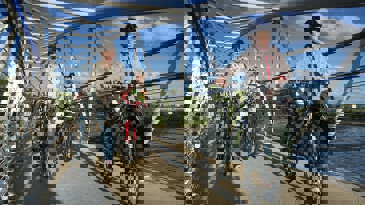 Family walking with bicycles over a bridge