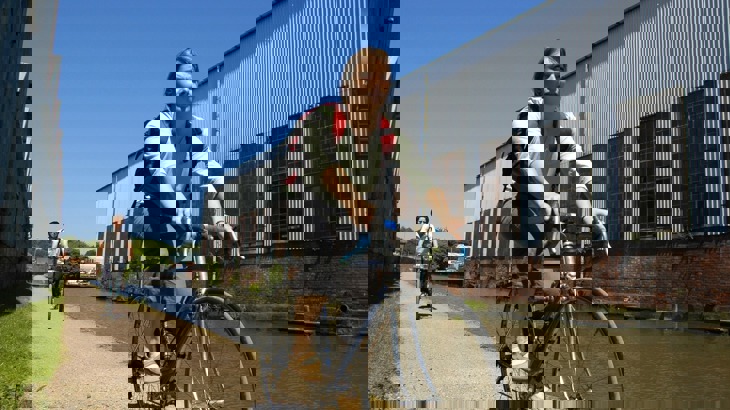 Two cyclists on canal towpath in industrial area