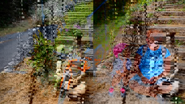 Mum and daughter sitting on steps with bicycles nearby