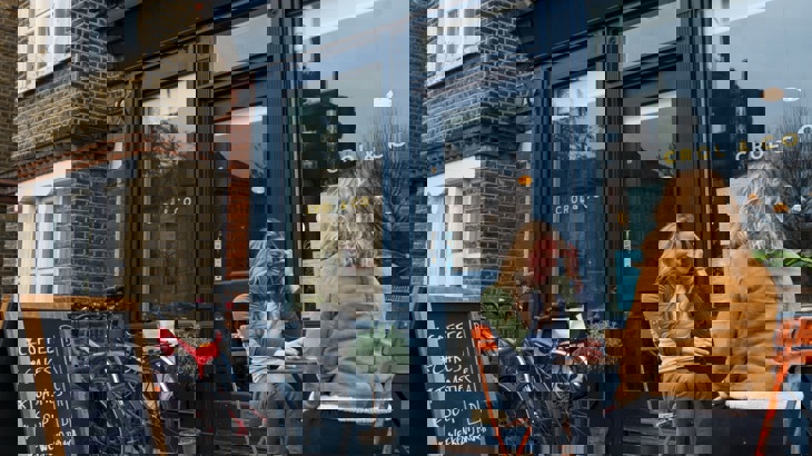 Two people chatting over coffee outside cafe with bikes