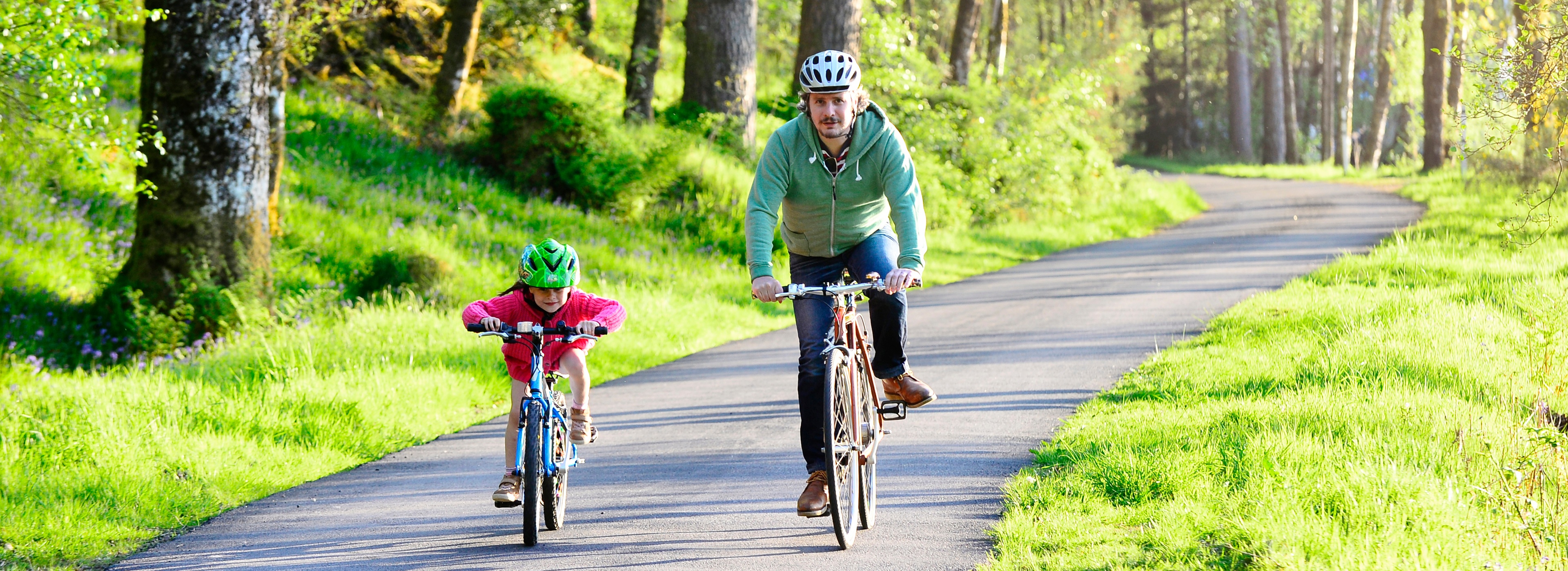 Man and child cycling on traffic-free path